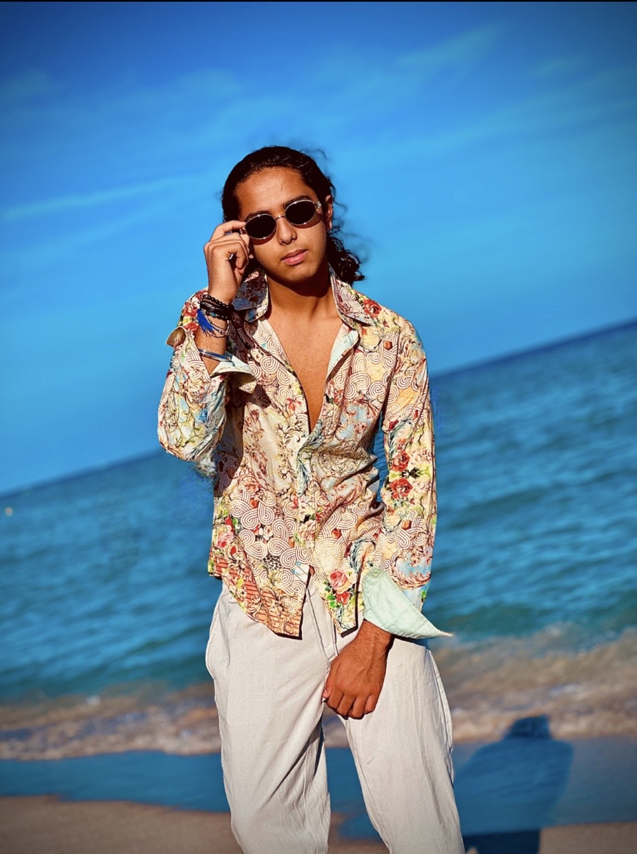 Aryan Rohira on a Miami beach with waves rolling in behind him